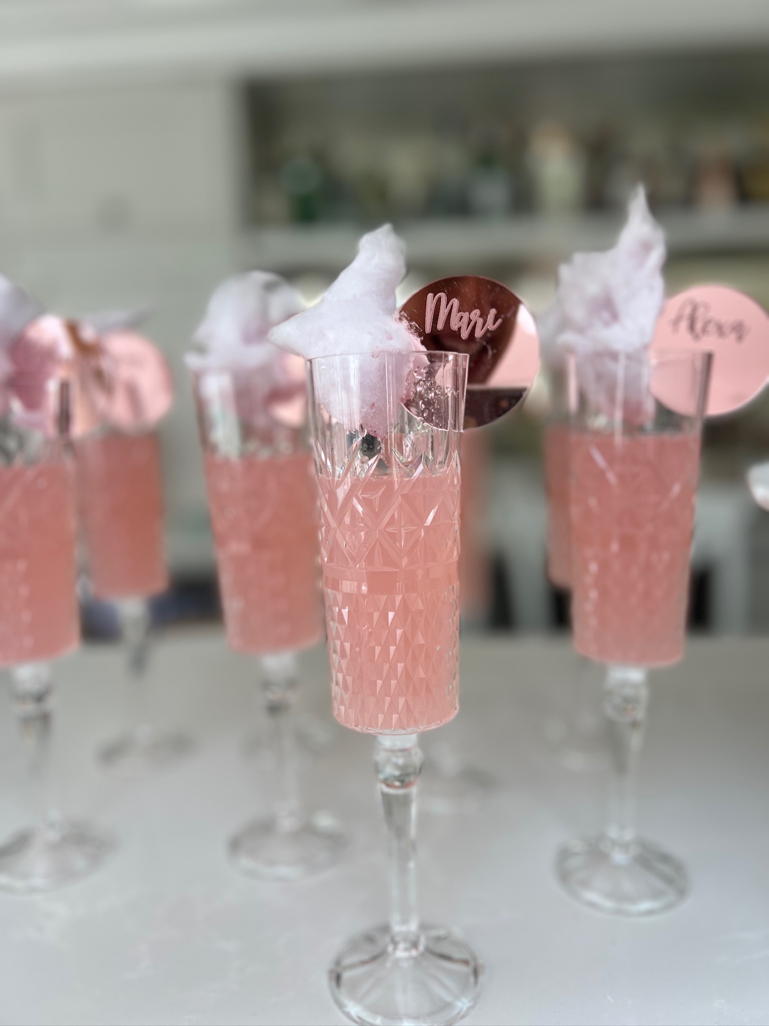 Pink mocktails with cotton candy garnish and rose gold place cards at a Wonder & Dash Spa Party