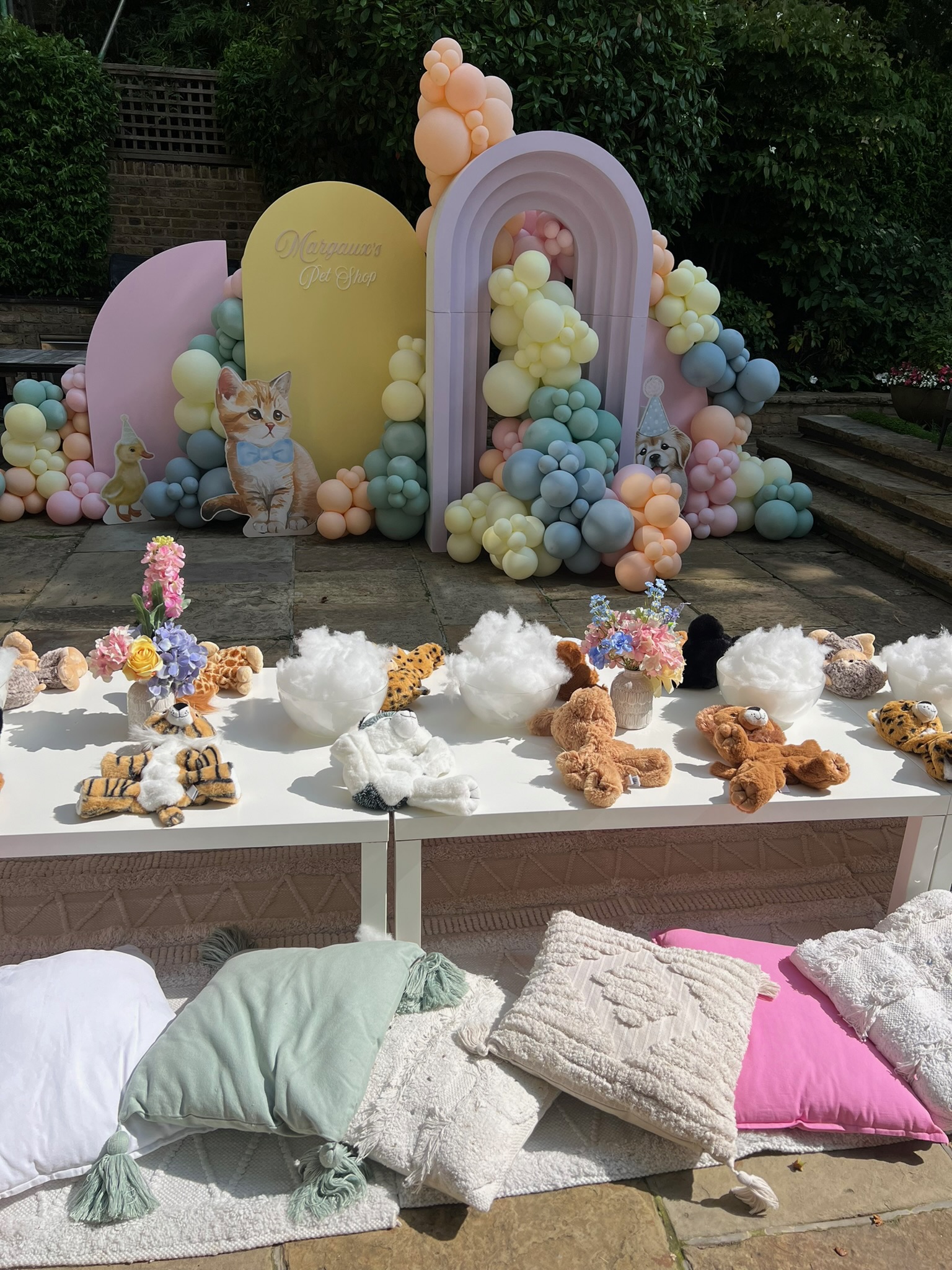 Pastel balloon arch backdrop and teddy-making station styled for a Wonder & Dash kids' workshop party